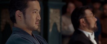 Movie still from “Fearless” (2006), directed by Ronny Yu – A person wearing a robe looking at something; Close Up shot, Over the shoulder angle