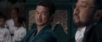 Movie still from “Fearless” (2006), directed by Ronny Yu – A person wearing a robe looking at the camera; Close Up shot, Over the shoulder angle