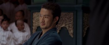 Movie still from “Fearless” (2006), directed by Ronny Yu – A person wearing a robe looking at the camera; Close Up shot, Over the shoulder angle