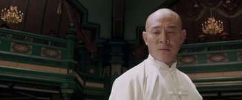 Movie still from “Fearless” (2006), directed by Ronny Yu – A man in a white shirt is standing in front of a green wall; Close Up shot, Low angle