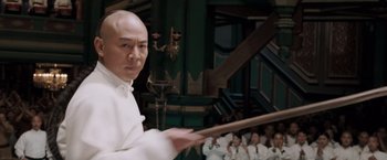 Movie still from “Fearless” (2006), directed by Ronny Yu – A man in a white shirt holding a wooden stick; Close Up shot, Low angle