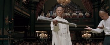 Movie still from “Fearless” (2006), directed by Ronny Yu – A man in a white robe holding a metal object; Medium shot, Low angle