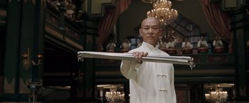 Movie still from “Fearless” (2006), directed by Ronny Yu – A man in a white shirt holding a metal rod; Medium shot, Low angle