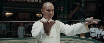 Movie still from “Fearless” (2006), directed by Ronny Yu – A man in a white shirt is holding a sword; Medium shot, Low angle