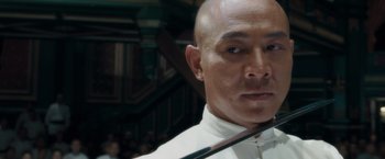 Movie still from “Fearless” (2006), directed by Ronny Yu – A man with a bow in his hair and wearing a white shirt; Close Up shot, Low angle