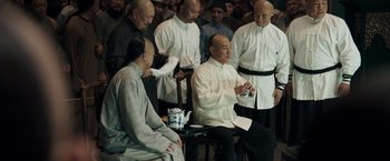 Movie still from “Fearless” (2006), directed by Ronny Yu – A group of men standing next to each other in a room; Medium shot, Over the shoulder angle