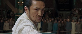 Movie still from “Fearless” (2006), directed by Ronny Yu – A person with a crowd in the background; Close Up shot, Over the shoulder angle