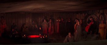 Movie still from “Fellini Satyricon” (1969), directed by Federico Fellini – A group of people standing in front of a fire pit; Wide shot, High angle