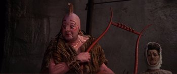 Movie still from “Fellini Satyricon” (1969), directed by Federico Fellini – A person with a red stick and a pink hat; Medium shot, High angle