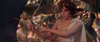 Movie still from “Fellini Satyricon” (1969), directed by Federico Fellini – A young man holding a bow and arrow in front of a mirror; Medium shot, High angle