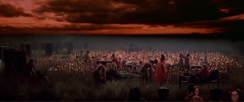 Movie still from “Fellini Satyricon” (1969), directed by Federico Fellini – A group of people standing in a field with lights; Extreme Wide shot, High angle