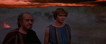 Movie still from “Fellini Satyricon” (1969), directed by Federico Fellini – A man standing next to another man in front of a painting; Medium shot, Over the shoulder angle