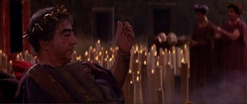 Movie still from “Fellini Satyricon” (1969), directed by Federico Fellini – A woman in a crowd of lit candles in the dark; Medium shot, Over the shoulder angle