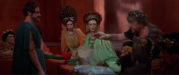 Movie still from “Fellini Satyricon” (1969), directed by Federico Fellini – Two women dressed in ancient clothing sitting in front of a bowl; Medium shot, Over the shoulder angle