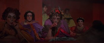 Movie still from “Fellini Satyricon” (1969), directed by Federico Fellini – A group of people dressed up in costumes; Medium shot, High angle