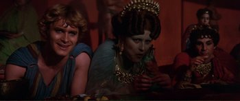 Movie still from “Fellini Satyricon” (1969), directed by Federico Fellini – A woman in a blue dress holding a drink; Close Up shot, Over the shoulder angle