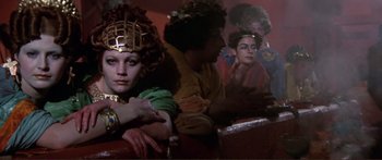 Movie still from “Fellini Satyricon” (1969), directed by Federico Fellini – A group of people sitting in a room; Close Up shot, Low angle