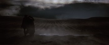 Movie still from “Fellini Satyricon” (1969), directed by Federico Fellini – A person standing in the middle of a field under a cloudy sky; Extreme Wide shot, Low angle