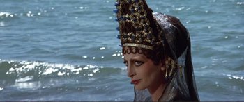 Movie still from “Fellini Satyricon” (1969), directed by Federico Fellini – A woman in a gold and blue headpiece standing in the water; Close Up shot, High angle