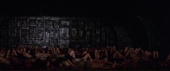 Movie still from “Fellini Satyricon” (1969), directed by Federico Fellini – A group of people laying on the ground in a dark room; Extreme Wide shot, High angle