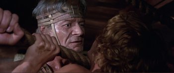 Movie still from “Fellini Satyricon” (1969), directed by Federico Fellini – An older man wearing a head dress and holding a sword; Close Up shot, Over the shoulder angle