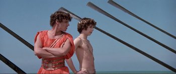 Movie still from “Fellini Satyricon” (1969), directed by Federico Fellini – Two young men standing next to each other on a boat; Medium shot, Low angle