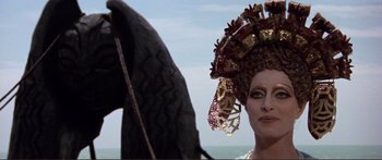 Movie still from “Fellini Satyricon” (1969), directed by Federico Fellini – A woman in a costume with a tire in the background; Close Up shot, Over the shoulder angle
