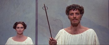 Movie still from “Fellini Satyricon” (1969), directed by Federico Fellini – A man holding a wooden stick in his hand; Medium shot, Low angle