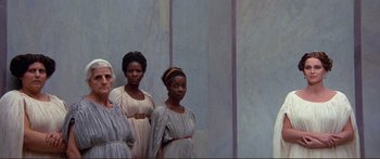 Movie still from “Fellini Satyricon” (1969), directed by Federico Fellini – A group of women standing next to each other in dresses; Wide shot, Low angle