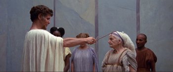 Movie still from “Fellini Satyricon” (1969), directed by Federico Fellini – A woman is holding a wand in front of a man; Medium shot, Low angle