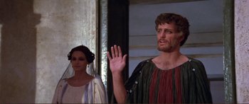 Movie still from “Fellini Satyricon” (1969), directed by Federico Fellini – A man and a woman standing next to each other in front of a wall; Medium shot, Over the shoulder angle