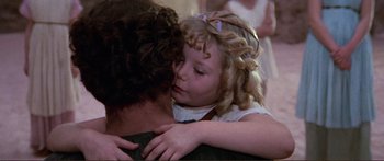 Movie still from “Fellini Satyricon” (1969), directed by Federico Fellini – A little girl is hugging a man in front of a wall; Close Up shot, Over the shoulder angle