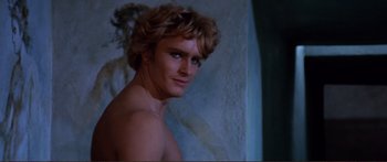 Movie still from “Fellini Satyricon” (1969), directed by Federico Fellini – A shirtless man with long blond curly hair; Close Up shot, Over the shoulder angle
