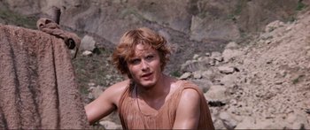 Movie still from “Fellini Satyricon” (1969), directed by Federico Fellini – A man with long red hair wearing a brown shirt; Close Up shot, Over the shoulder angle