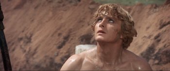 Movie still from “Fellini Satyricon” (1969), directed by Federico Fellini – A shirtless man with wet hair looking upward; Close Up shot, Low angle