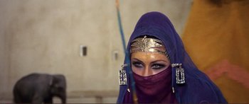 Movie still from “Fellini Satyricon” (1969), directed by Federico Fellini – A woman in a purple headscarf and gold jewelry; Close Up shot, Over the shoulder angle
