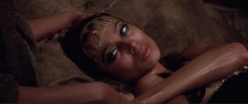 Movie still from “Fellini Satyricon” (1969), directed by Federico Fellini – A woman laying on the ground wearing a camouflage headband; Close Up shot, Overhead angle