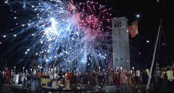 Movie still from “Fellini's Casanova” (1976), directed by Federico Fellini – A crowd of people standing around a building with fireworks in the background; Extreme Wide shot, Low angle