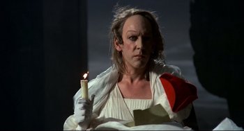Movie still from “Fellini's Casanova” (1976), directed by Federico Fellini – A woman holding a lit candle in a dark room; Medium shot, Low angle