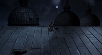 Movie still from “Fellini's Casanova” (1976), directed by Federico Fellini – A man is climbing on the roof of a building at night; Wide shot, Overhead angle