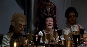 Movie still from “Fellini's Casanova” (1976), directed by Federico Fellini – A woman sitting at a dinner table wearing a headpiece; Medium shot, High angle