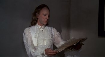 Movie still from “Fellini's Casanova” (1976), directed by Federico Fellini – A woman in a white dress reading a newspaper; Medium shot, Over the shoulder angle