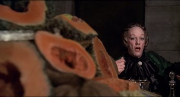 Movie still from “Fellini's Casanova” (1976), directed by Federico Fellini – A woman in a black leather jacket sitting in front of a pile of fruit; Close Up shot, Over the shoulder angle