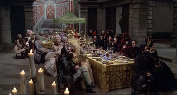 Movie still from “Fellini's Casanova” (1976), directed by Federico Fellini – A group of people sitting around a table with food on top of it; Wide shot, High angle