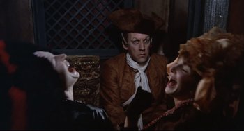 Movie still from “Fellini's Casanova” (1976), directed by Federico Fellini – A man and two women are sitting on a bench; Medium shot, High angle