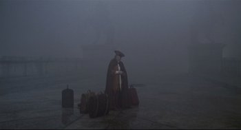 Movie still from “Fellini's Casanova” (1976), directed by Federico Fellini – A man standing in the middle of a street with luggage; Wide shot, High angle