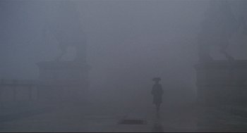 Movie still from “Fellini's Casanova” (1976), directed by Federico Fellini – A person with an umbrella walking in the fog; Extreme Wide shot, Low angle