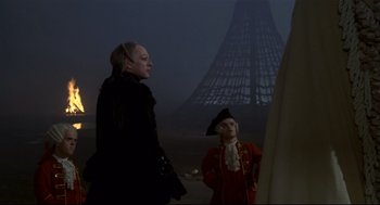 Movie still from “Fellini's Casanova” (1976), directed by Federico Fellini – A man and a woman standing next to each other in front of a tower; Medium shot, Low angle