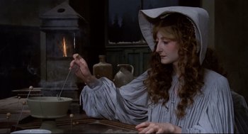 Movie still from “Fellini's Casanova” (1976), directed by Federico Fellini – A woman in a white hat is stirring something in a pot; Medium shot, High angle