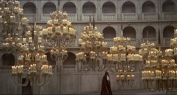 Movie still from “Fellini's Casanova” (1976), directed by Federico Fellini – A man walking in front of a building with a lot of lights hanging from it; Extreme Wide shot, Low angle
